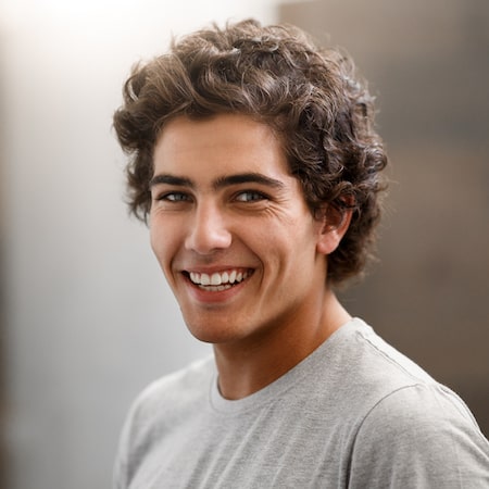 A young man with curly brown hair smiling 