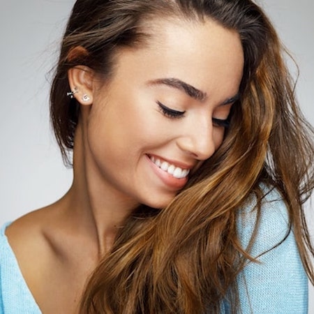 A young women looking down smiling with long brown hair 