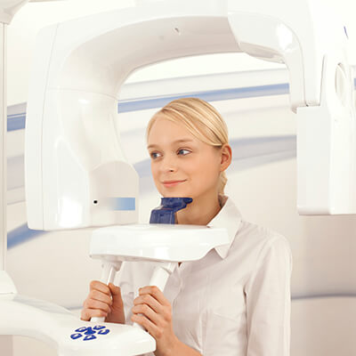A woman standing with her hands holding handles inside a CT scanner